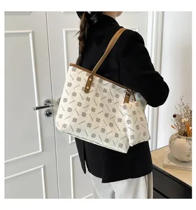 Détail d'un sac cabas imprimé avec poignées en cuir marron et petite pochette
