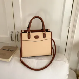 Minimalist color-block tote bag in cream and brown leather with adjustable shoulder strap