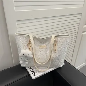 Beige tote bag with star embroidery and cloud charm on a black leather sofa