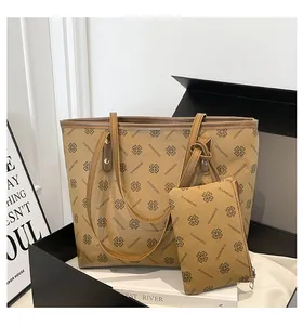 Détail d'un grand sac cabas kaki imprimé trèfles avec sa pochette dans un coffret cadeau