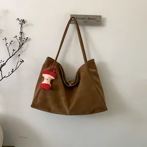 Minimalist vintage brown suede tote bag with cute apple pendant on white wall