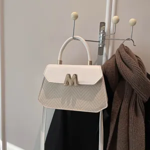 Chic beige woven shoulder bag with white leather flap and gold M-letter clasp