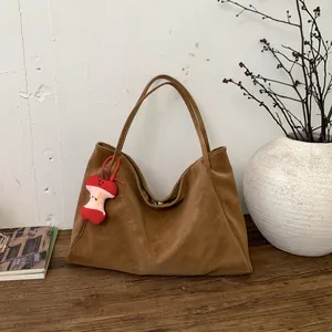 Retro brown soft leather tote bag with a cute apple plush charm in a lifestyle setting