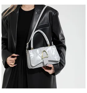 Détail du sac argenté avec imprimé abstrait et boucle dorée sur veste en cuir noir