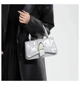 Détail d'un sac à main argenté avec imprimé graffiti et boucle métallique sur le modèle