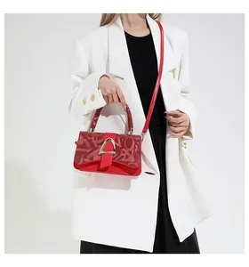 Détail du sac à main carré rouge avec boucle dorée en D et rabat texturé sur blazer blanc