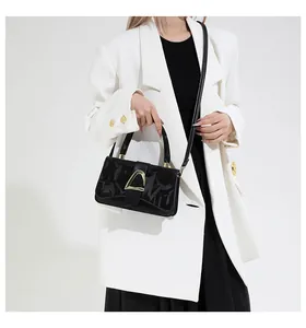 Détail de la boucle dorée en D sur sac à main noir avec lettres embossées chic