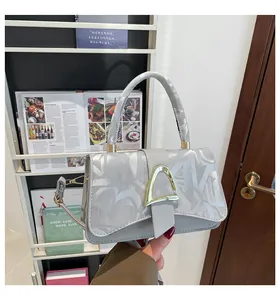 Détail d'un sac bandoulière gris avec boucle en métal doré et motif abstrait