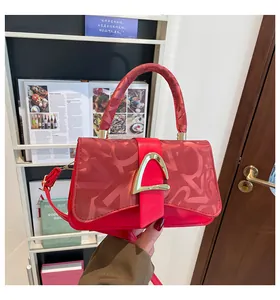 Détail du sac rouge texturé avec boucle en D dorée et poignée élégante pour femme