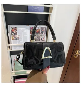 Gros plan du sac en cuir noir mat avec texture gaufrée et fermoir en métal doré en D