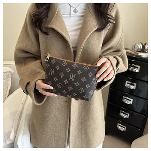 Macro detail of monogrammed brown cosmetic pouch with gold zipper and stylish pattern