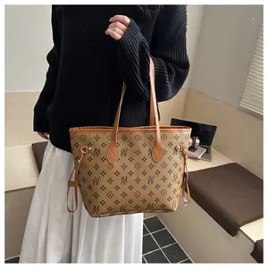 Detail of printed tote bag with brown leather straps and patterned floral monogram print