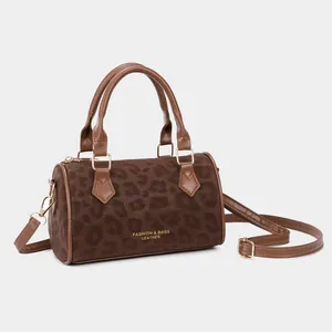 Chic leopard print cylinder handbag with gold hardware and brown leather straps