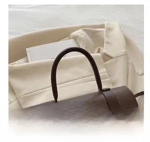 Détails d'un sac à main marron foncé en cuir grainé avec boucle et poignée ronde épaisse