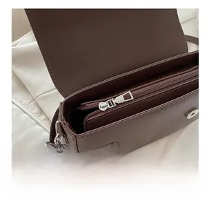 Détail de la fermeture éclair fluide et des boutons aimantés du sac en cuir marron