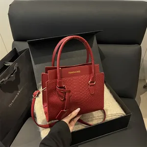 Classic red snakeskin embossed handbag with top handles and a gold fashion logo detail