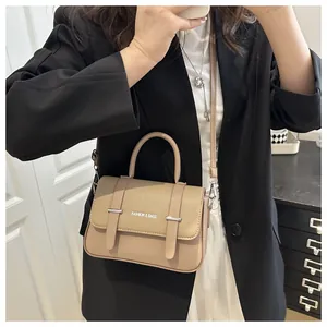 Vue portée d'un sac boîte beige avec bandoulière réglable et poignée supérieure