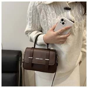 Détail d'un sac boîte marron foncé en cuir grainé avec boucles en métal argenté