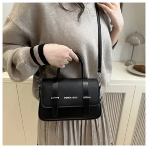 Detalle del bolso bandolera de cuero granulado negro con correas decorativas y tonos plata