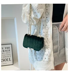 Detail of dark green velvet mini bag with vertical stripes and golden chain strap on model