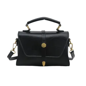 Retro black leather handbag with a top handle and gold-tone hardware on white background