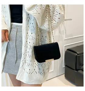 Detalle de bolso de cadena en terciopelo negro con barra dorada y textura elegante