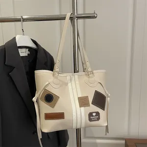 Large vintage-style cream tote bag with stylish patchwork design and thin shoulder straps