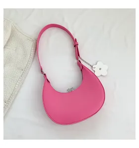 Detail of pink crescent bag showing silver zipper, adjustable strap, and flower charm