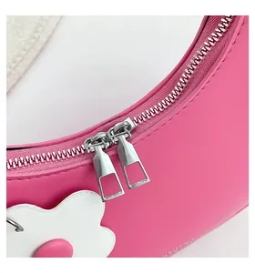 Detail of rose pink crescent bag with silver zipper and white floral accessory