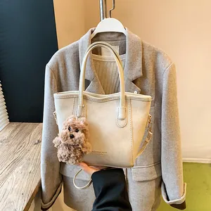 Chic beige tote bag with cute brown bear charm and adjustable shoulder strap