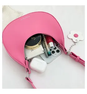 Pink crescent shoulder bag showing interior space for phone and makeup accessories