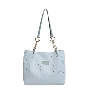 Borsa tote celeste con motivi a stelle argentate e catena dorata su sfondo bianco