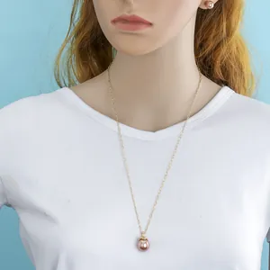 Detail of lavender pearl pendant necklace and gold chain worn by a model in light blue