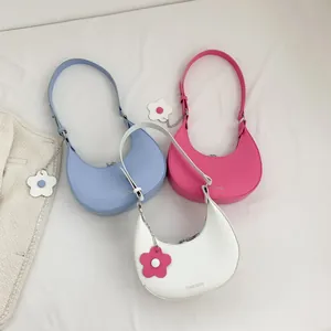 Three half-moon hobo shoulder bags in blue, pink, and white with floral pendants