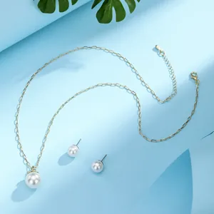 Detailed close-up of gold-plated necklace and pearl earrings set on a tropical background