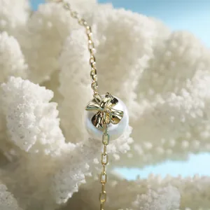 Macro shot of gold bow knot necklace with white pearl on white coral background