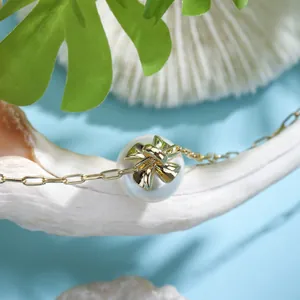 Detailed macro view of a gold bowknot pendant with a round pearl on a link chain necklace