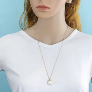 Detailed close-up of natural shell pearl necklace and gold paperclip chain on model