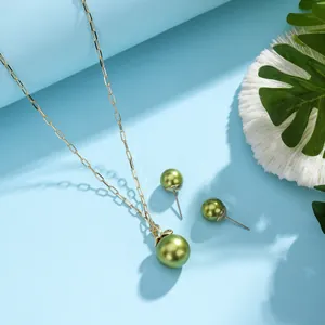 Detailed close-up of gold necklace and green pearl studs with coral and leaves