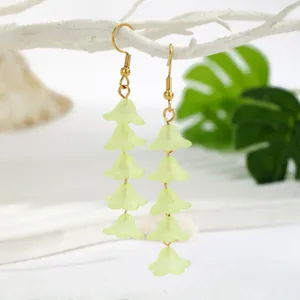 Detailed view of handmade green resin lily of the valley tassel earrings on a display
