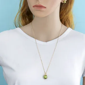 Detail of gold chain necklace and matching green pearl earrings on a model