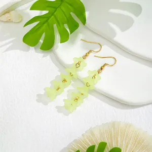 Close-up of four-layered frosted yellow resin flower drop earrings with gold ear hooks