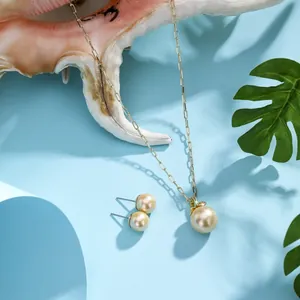 Detail of champagne gold pearl jewelry set on a sea shell with tropical leaves