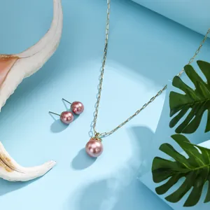 Detail of gold-plated link necklace and purple pearl earrings with seashells