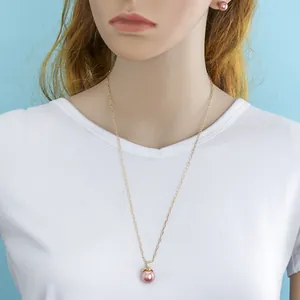 Detailed view of pink pearl necklace and stud earrings set on a model with gold chain