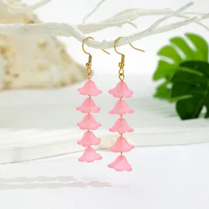 Detail of matte pink resin lily of the valley flower drop earrings with golden hooks