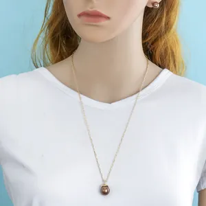 Detail shot of brown pearl necklace and matching stud earrings worn on a model