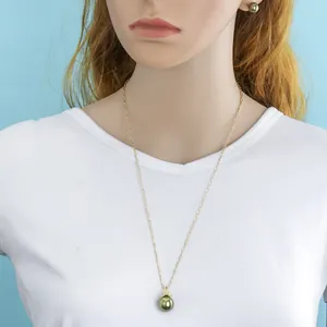 Detail showing an olive green pearl necklace and stud earrings set on a model