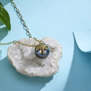 Detail of grey pearl pendant necklace with gold bow on white stone and blue backdrop