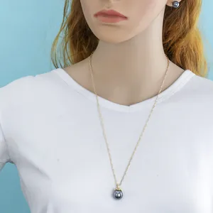 Detail of dark pearl necklace and earrings set with gold leaf motifs on model